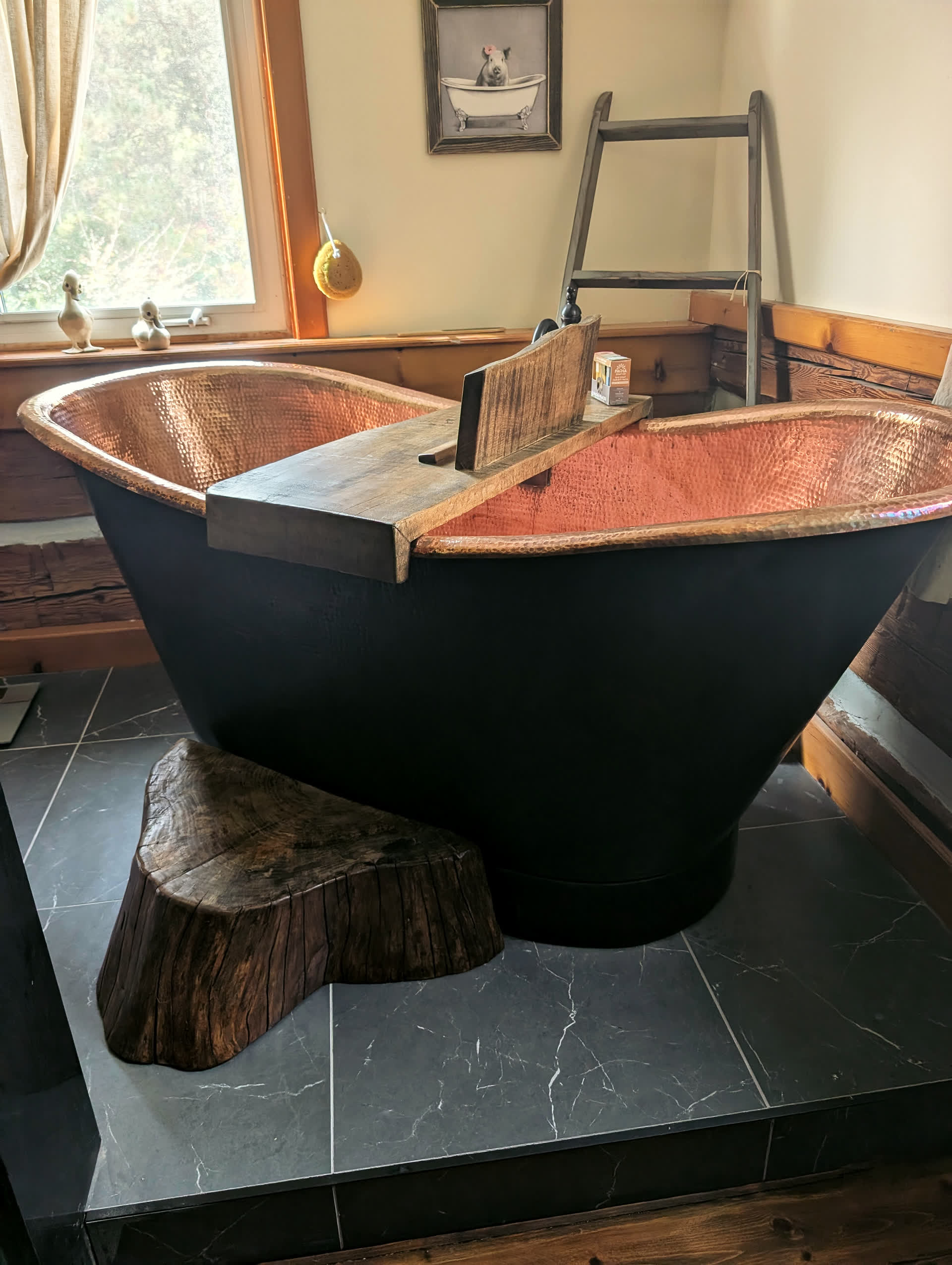 Copper soaking tub resting on hand-finished wood stumps over stone tile