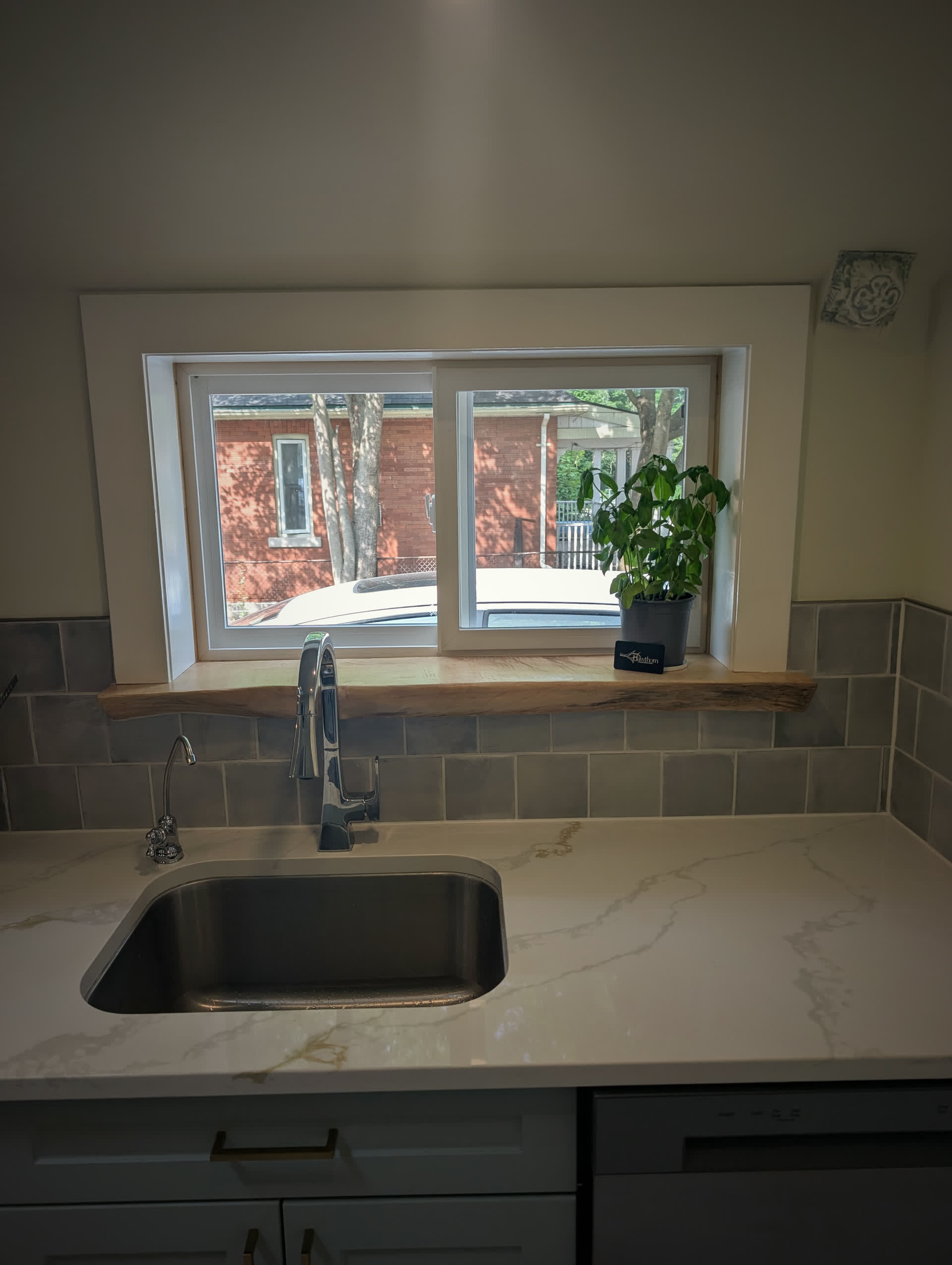 Live-edge wood window sill set against a quartz counter above a kitchen sink